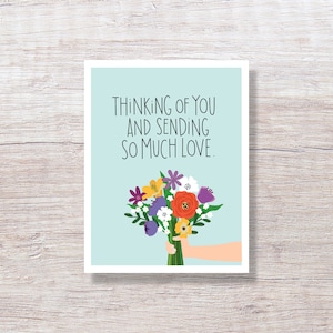 May include: A light blue card with the text "Thinking of you and sending so much love."  A hand holds a bouquet of colorful flowers, including purple, yellow, orange, and white.