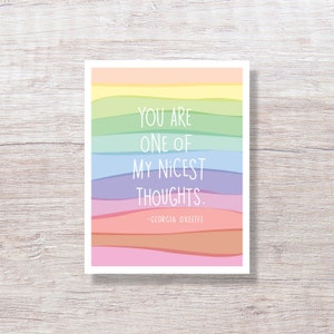May include: A rectangular art print with a colorful rainbow wave design. The text "YOU ARE ONE OF MY NICEST THOUGHTS." is displayed in white, along with the author's name, Georgia O'Keeffe.