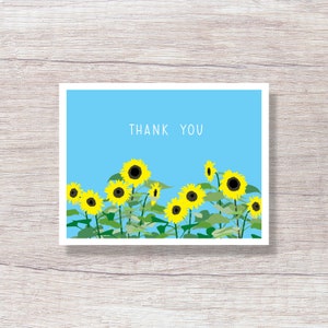 May include: A blue card with the text "THANK YOU" in white. The card features a row of yellow sunflowers with black centers against a blue background.