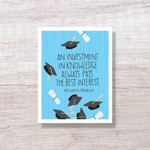 May include: A graduation-themed greeting card with a light blue background and white vertical stripes. The card features black graduation caps and rolled diplomas scattered around the text: "AN INVESTMENT IN KNOWLEDGE ALWAYS PAYS THE BEST INTEREST." -BENJAMIN FRANKLIN.