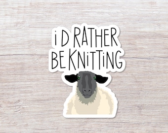 May include: A white sticker with black text that reads "I'd rather be knitting" and a cartoon image of a sheep with black ears and a black face.