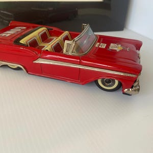 May include: A vintage red convertible toy car with chrome accents. The car has a white windshield, yellow and red seats, and the word "GONE" is printed on the back. The car's wheels have white sidewalls.