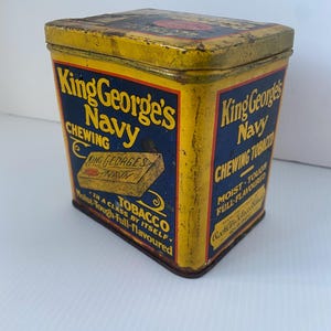 May include: Vintage King George's Navy Chewing Tobacco tin. The rectangular tin has a yellow background with blue panels and red accents. Text includes "King George's Navy Chewing Tobacco" and "Moist-Tough-Full-flavoured". The tin is slightly worn.