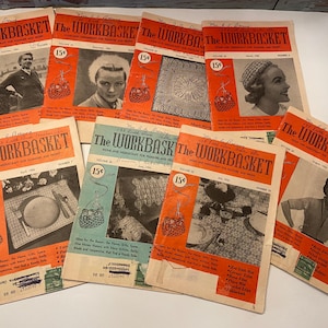 May include: A selection of vintage "The Workbasket" magazines, with orange and teal covers. Each magazine displays illustrations and photographs, with the price of 15 cents on each cover. The magazines focus on crafts and home decor.