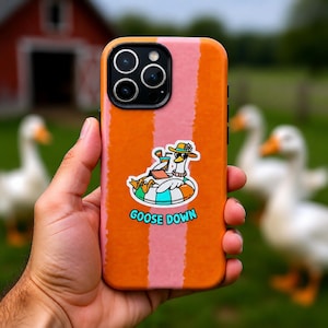 Puede incluir: Funda de teléfono a rayas naranjas y rosas con un dibujo de un ganso con sombrero y gafas de sol relajándose en un flotador. El texto "GOOSE DOWN" está debajo.