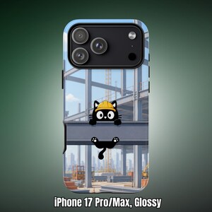 Op de afbeelding: Een glanzend telefoonhoesje voor de iPhone 17 Pro Max met een cartoon zwarte kat met een gele veiligheidshelm, zittend op een stalen constructiebalk. De achtergrond toont een bouwplaats met stalen balken en een verre stadsskyline.