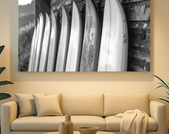 May include: Black and white photograph of surfboards leaning against a weathered wooden wall. The surfboards are arranged in a row, with their pointed tips facing upwards. The image evokes a coastal or beach theme.