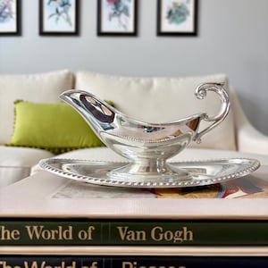 May include: A white ceramic mug with a black handle and the text "But First, Coffee" in a bold, black font. The mug is set against a blurred background, suggesting a cozy setting. The mug appears to be approximately 4 inches tall.