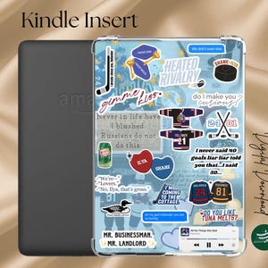 May include: Kindle Insert with a black cover and a clear case decorated with hockey-themed stickers. The stickers include text like "gimme kiss," "Heated Rivalry," and jersey graphics. The background is light blue.