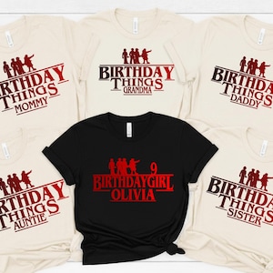 May include: A collection of beige and black t-shirts with the words "Birthday Things" in a red and black design. The shirts are labeled "Mommy", "Grandma", "Daddy", "Auntie", "Birthday Girl Olivia", and "Sister".