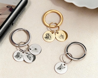 May include: Keychains with engraved dog portraits. The keychains have round metal pendants with detailed images of various dog breeds. The keychains are silver and gold in color, with a ring for attaching keys.