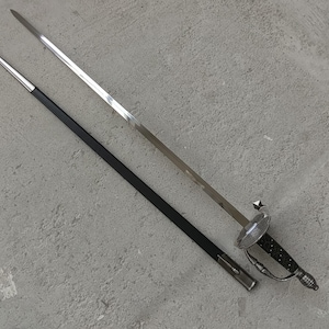 May include: A silver and black rapier sword with a decorative hilt and a black scabbard. The sword's blade is long and slender, and the hilt features a detailed design. The scabbard is black with a silver tip.