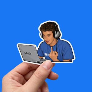 Può includere: Un adesivo illustrato raffigurante una persona con capelli castani ricci che indossa grandi cuffie nere e argento, vestita con una maglietta blu, che guarda un portatile Sony VAIO argento mentre mostra il dito medio. Bordo bianco.