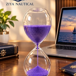 Può includere: Una clessidra in vetro trasparente riempita con sabbia viola vibrante. La clessidra presenta una forma arrotondata e bulbosa con un collo stretto dove la sabbia scorre dalla camera superiore a quella inferiore. È visibile il logo ZIYA NAUTICAL.