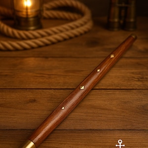 以下が含まれることがあります： 真鍮のアクセントと装飾的なスタッドが付いた木製の杖。 杖は濃い茶色の仕上げと真鍮の先端が付いています。 ZIYA NAUTICALのロゴが見えます。 海をテーマにしています。