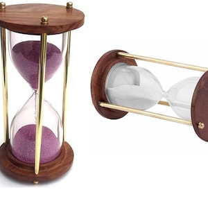 Puede incluir: Dos relojes de arena con marcos de madera y detalles de latón. Un reloj de arena contiene arena morada, el otro arena blanca. Los relojes de arena están hechos de vidrio y madera y están diseñados para medir el tiempo.
