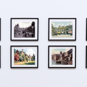 Op de afbeelding: Acht ingelijste vintage prenten van landschappen en architectuur hangen aan een witte muur. De prenten tonen kleurrijke en zwart-wit afbeeldingen van gebouwen, straten en natuurlandschappen. Elke prent zit in een zwart frame.