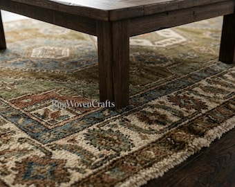 May include: A rectangular area rug featuring a complex pattern in shades of olive green, rust red, cream, and slate blue, with a fringed edge. The rug is positioned beneath a dark brown wooden table with four square legs on a dark wood floor.