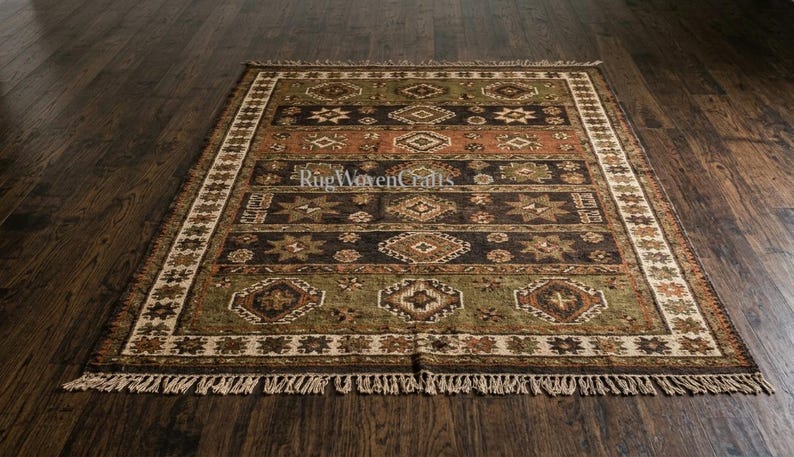 May include: A rectangular area rug featuring horizontal bands in shades of olive green, dark brown, and terracotta orange. The rug displays repeating geometric diamond and star patterns throughout, finished with a cream-colored fringe at both ends.