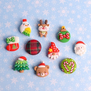 May include: A collection of Christmas-themed embellishments, including a snowman, reindeer, Santa Claus, and a Christmas tree. The decorations are in various colors, such as red, green, and white, and are arranged on a light blue snowflake patterned background.