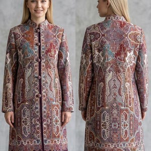 Könnte beinhalten: Ein langer, gemusterter Mantel mit Stehkragen und Knopfverschluss. Der Mantel hat ein Paisley-Design in Burgunder-, Braun- und Türkistönen. Die Länge beträgt 99 cm. Vorder- und Rückansicht.