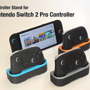 May include: Black Nintendo Switch Pro controller stands with blue, orange, and grey accents. The stands hold the controllers upright. A Nintendo Switch console is also in the image, displaying a game screen. Text reads: "Controller Stand for Nintendo Switch 2 Pro Controller."