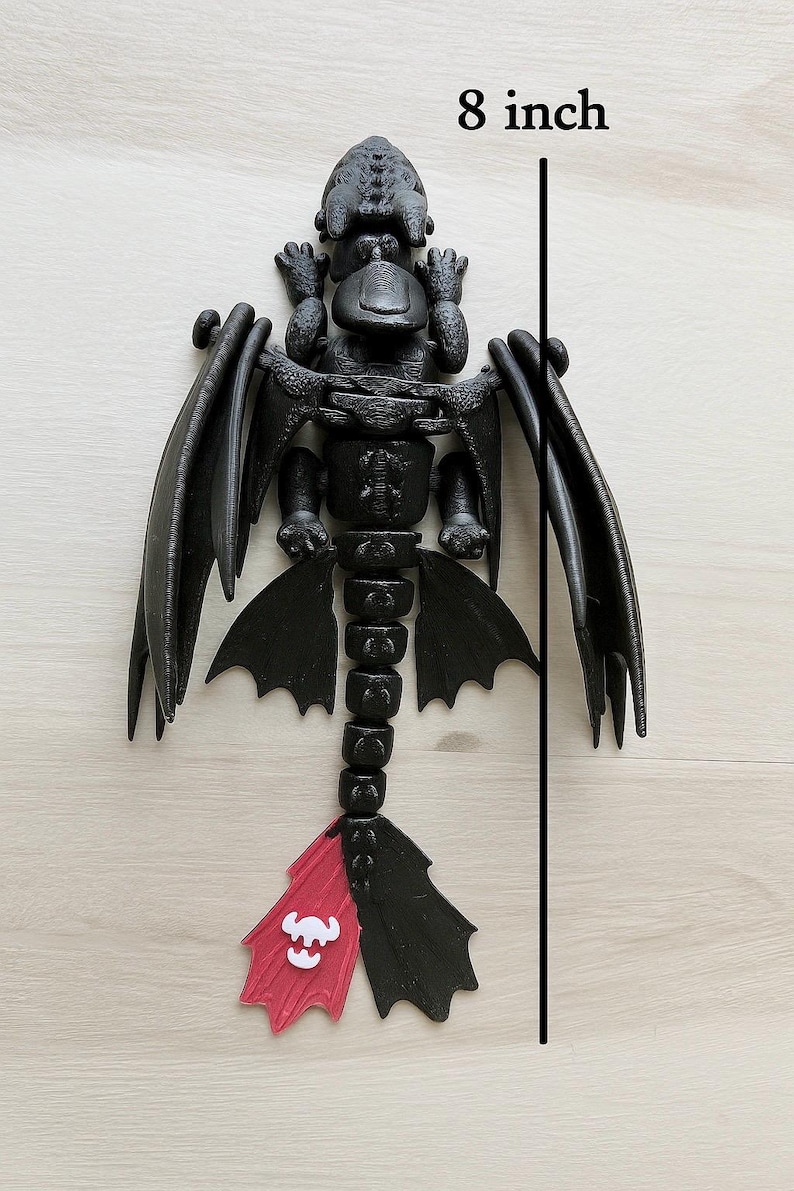 May include: A black dragon figurine, approximately 8 inches in length, with articulated wings and tail. The tail features a red and white design. The dragon is posed on a light wood surface.