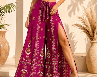 May include: Magenta wide-leg pants featuring a high-waisted tie-front closure and a prominent side slit. The fabric is adorned with a repeating geometric and floral pattern in shades of white, yellow, and orange, arranged in vertical columns.