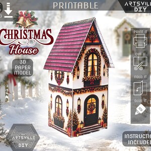 May include: A 3D paper model of a two-storey Christmas house with a red roof, white walls, and festive holiday decorations including wreaths and garlands. The printable design features windows, a door, and text reading Christmas House, Artsville DIY.