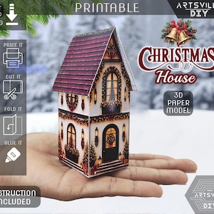 Peut inclure: Un modèle en papier 3D d'une maison de Noël avec un toit rouge foncé et des murs blancs ornés de fenêtres, de portes et de décorations festives. Le modèle comporte le texte PRINTABLE, CHRISTMAS HOUSE, 3D PAPER MODEL et ARTSVILLE DIY.