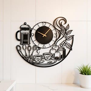 Puede incluir: Un reloj de pared de metal negro con esfera circular y manecillas doradas. El diseño incluye siluetas de una prensa francesa, cuatro cucharas, dos tazas en una bandeja, bolsitas de té, un bote y ramas de cafeto con hojas y granos de café.