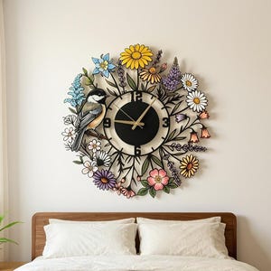 Könnte beinhalten: Eine runde Wanduhr mit schwarzem Zifferblatt, goldenen Zeigern und den Ziffern 3, 6, 9 und 12. Der Rahmen ist mit einer bunten Anordnung illustrierter Blumen, grüner Blätter und einem kleinen Vogel auf einem Ast auf der linken Seite verziert.