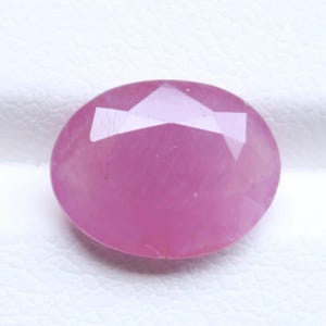 Peut inclure: Une pierre précieuse rose de forme ovale à facettes avec une surface lisse et polie. La pierre présente une teinte rose translucide et vibrante avec des inclusions internes visibles et des facettes géométriques qui reflètent la lumière.