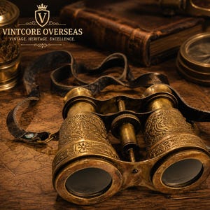 May include: Antique brass binoculars featuring intricate floral engravings on the barrels, a central focus adjustment wheel, and a worn black leather neck strap. The metal surface displays a weathered patina, and the lenses are clear and circular.