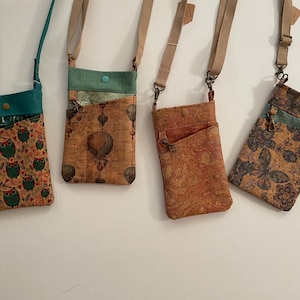 May include: Four rectangular crossbody bags with adjustable beige or teal straps. The bags feature various patterns including green owls, hot air balloons, a solid cork texture, and a floral butterfly print, each with a top flap and snap closure.