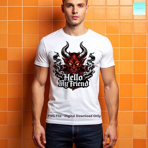 May include: White t-shirt featuring a red devil graphic with horns, a menacing expression, and the text "Hello My Friend." The design is surrounded by black smoke-like elements. The shirt is worn by a person.