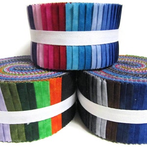 May include: Three rolls of fabric scraps in various colours, including purple, green, orange, blue, and grey. The fabric is rolled and tied with a white band.
