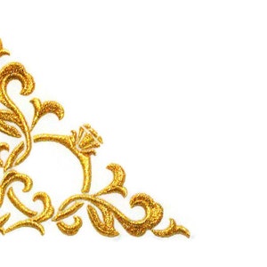 May include: A gold corner design with intricate floral details. The design features a stylized flower with leaves and swirls.