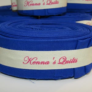 May include: A roll of blue fabric with a white label that reads "Kenna's Quilts" in pink lettering.