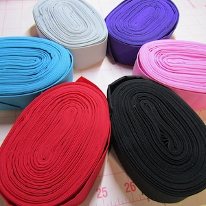 May include: Six rolls of fabric in different colors: light blue, gray, purple, pink, red, and black. The fabric is rolled up in a circle and is about 2 inches wide.