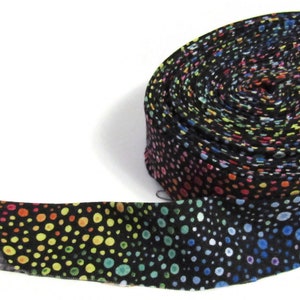 May include: A roll of black fabric with a rainbow polka dot pattern. The fabric is rolled up and tied with a white string.