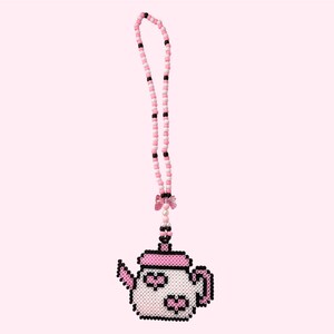 May include: A beaded necklace featuring a pixelated teapot pendant. The necklace is made of pink, white, and black beads. The teapot is white with pink and black accents. A pink bow and pearl accent the design. The background is a solid light pink.