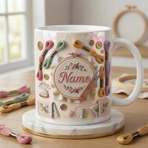 Puede incluir: Taza de cer&aacute;mica blanca decorada con elementos tem&aacute;ticos de bordado. El dise&ntilde;o incluye madejas de hilo de varios colores, bastidores de bordado, tijeras y el nombre "Name". La taza se encuentra sobre un posavasos de m&aacute;rmol.