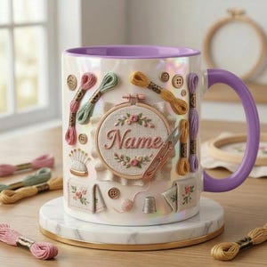 Puede incluir: Una taza de cer&aacute;mica blanca con asa y borde morados, decorada con adornos tem&aacute;ticos de bordado. La taza presenta carretes de hilo, botones y un dise&ntilde;o bordado central con el nombre "Name".