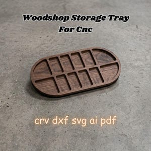 May include: An oval wooden storage tray with twelve rectangular compartments, featuring the text Woodshop Storage Tray For Cnc and crv dxf svg ai pdf. The tray has a dark brown wood grain finish and is designed for organization and storage.