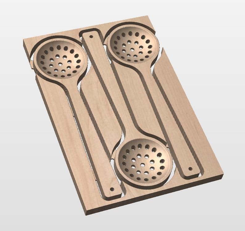 May include: A light-colored wooden board featuring two recessed, circular, perforated ladles or skimmers. The board has a rectangular shape with cutouts that mirror the shape of the two long-handled kitchen utensils nested within the wood.