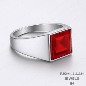 Puede incluir: Anillo de plata con una gran gema roja brillante de forma cuadrada. El anillo tiene un dise&ntilde;o simple y moderno con un acabado pulido. La gema est&aacute; engastada en un bisel cuadrado, y la banda es lisa y ancha.