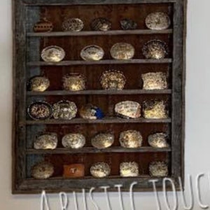 May include: A rustic wooden display shelf with multiple small, decorative objects. The objects are various shapes and colors, including gold, silver, and brown. The shelf has a weathered appearance, with the text "A RUSTIC TOUCH" at the bottom.
