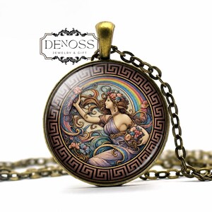 May include: A round bronze pendant necklace featuring a glass cabochon with an illustration of a woman in a flowing dress surrounded by flowers and a rainbow, framed by a black Greek key border. The text DENOSS JEWELRY & GIFT is visible.