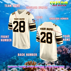May include: Two cream-coloured football jerseys with black and gold accents. The front jersey displays the number "28" and the text "TEAM NAME". The back jersey shows the number "28" and "YOUR NAME". The image includes the text "Customize Football Jerseys According To Your Preferences".